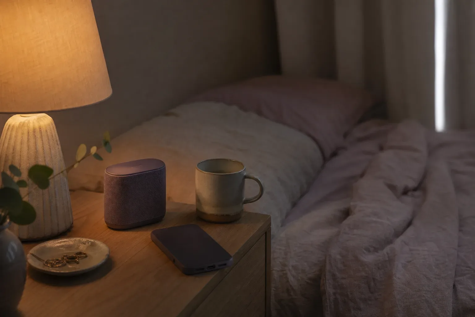 Bedside speaker glowing softly beside folded linen