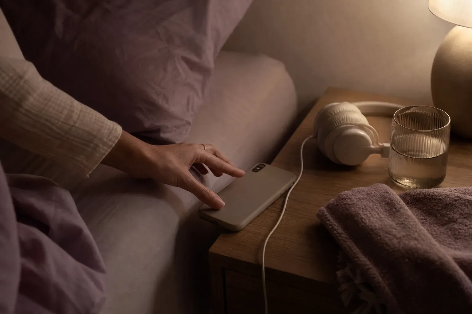 Phone resting beside headphones on a quiet bed