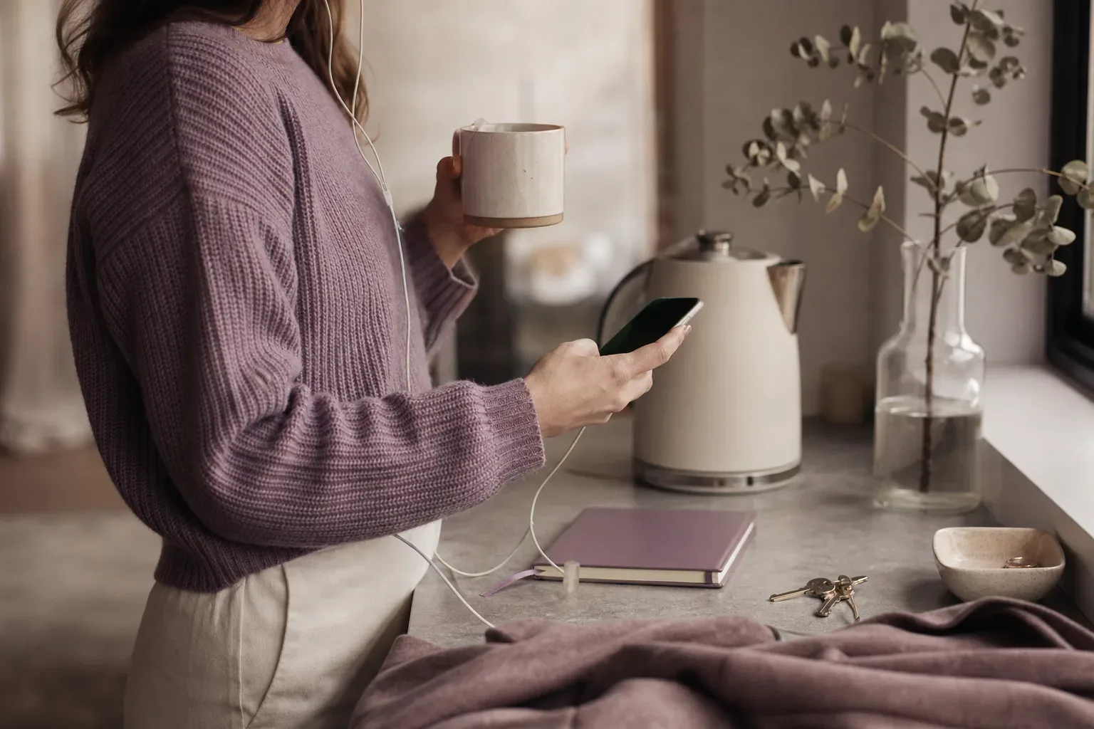 Donna che ascolta un audio accanto a una finestra al mattino